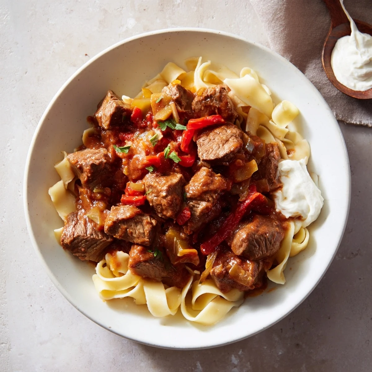 Hearty Hungarian Goulash, rich with beef and paprika, served atop fluffy egg noodles, ready to be enjoyed.