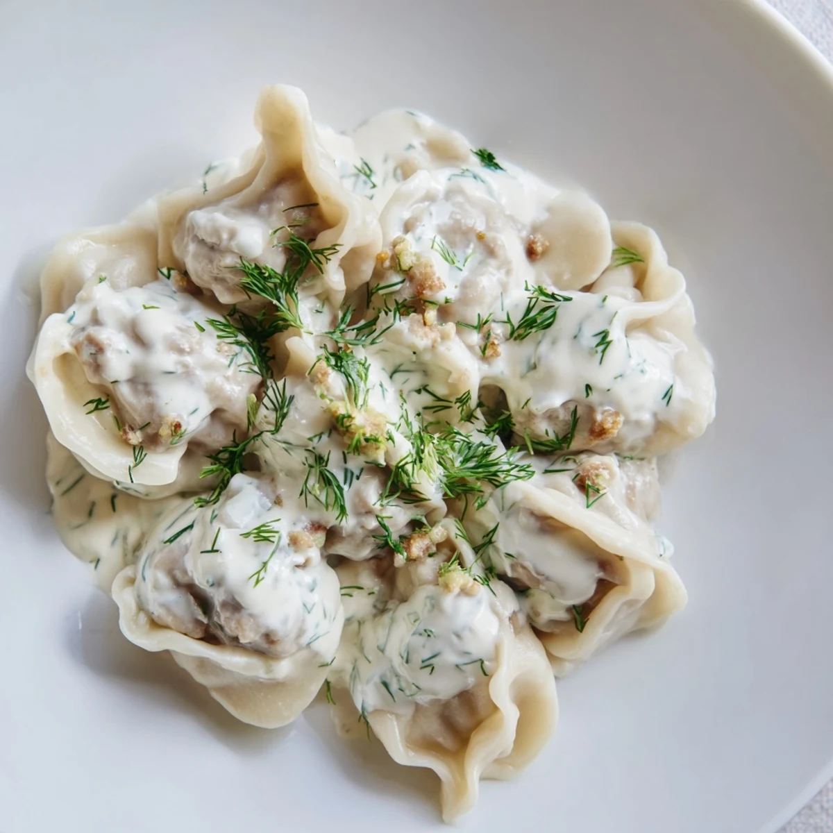 Steaming hot Russian pelmeni, tender meat dumplings, resting in creamy sour cream sauce.