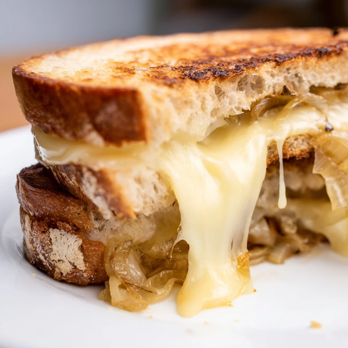 Toasted golden brown, the sandwich reveals a gooey Gruyère and caramelized onion filling between crispy rustic bread slices.