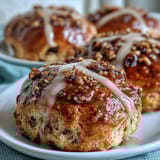 Fragrant hot cross buns glazed with citrus, topped with piped crosses, and served fresh from the oven for a festive treat.