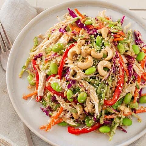 Colorful bowl of Edamame Crunch Chicken Salad featuring shredded chicken, crisp cabbage, and carrots tossed with a zesty ginger dressing.