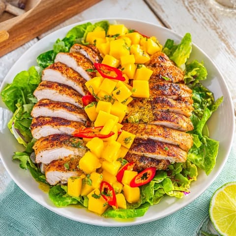 Perfectly grilled chicken breasts topped with colorful mango salsa ready to fill lettuce wraps.
