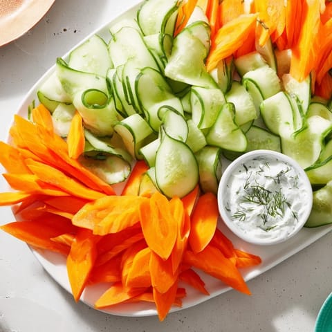 Beautifully arranged Veggie Platter with vibrant cucumber and carrot fans, ready to serve with a tangy dip.
