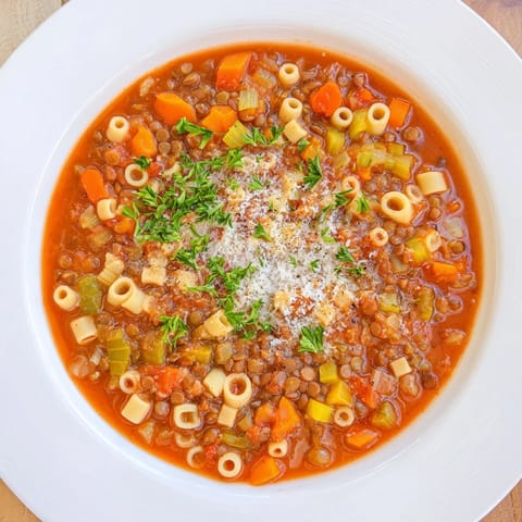 Hearty Italian-style ditalini and lentil soup simmering in a pot with vegetables and herbs, ready to serve.