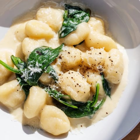 Tender gnocchi coated in a rich, velvety garlic cream sauce with wilted spinach leaves.