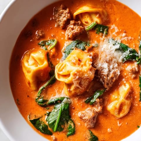 Hearty Tuscan Tortellini Soup served with crusty bread, showcasing the creamy tomato broth and melted Parmesan.