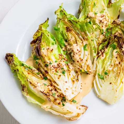 Freshly made tahini sauce, creamy and pale beige, poured over tender roasted cabbage wedges on a serving platter.