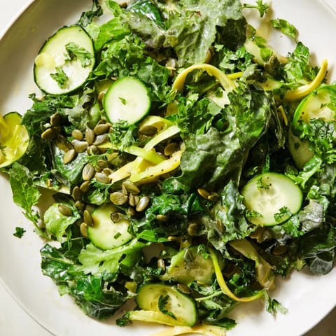 Freshly tossed Glowing Green Salad with crunchy vegetables and pumpkin seeds, drizzled with tangy vinaigrette.