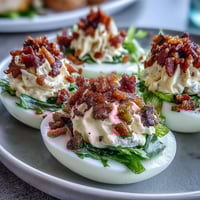 BLT Deviled Eggs with Crispy Bacon Crumbles: Creamy yolk filling topped with crunchy bacon, juicy tomatoes, and fresh lettuce for a BLT twist.
